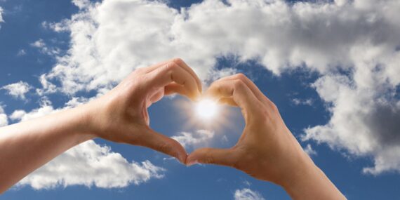 Heart shaped hands with cloud in the sky